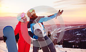 Concept friends travel love winter sport. Happy couple man and woman snowboarders background sunset ski resort
