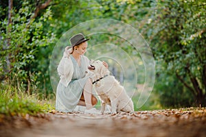 Concept Friendship girl with hat and golden retriever. Pretty young woman with dog on background summer park