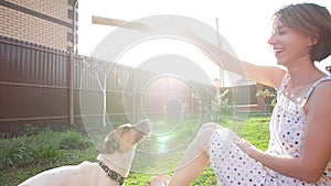 Concept of friendship and pets. Happy young woman and dog having fun at grass