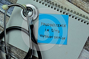 Concept of Fruorescence In Situ Hybridization write on sticky notes with stethoscope isolated on Wooden Table
