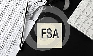 Concept FSA message on sticker with glasses,chart and calculator on the black background