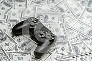 Concept of gaming addiction. Close up photo of gamepad on the money background.