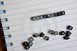 Concept of Gastritis on wooden cubes with books in background