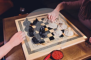 concept of Georgian cuisine. black and white khinkali stand on a chessboard. female hand takes khinkali. khinkali with