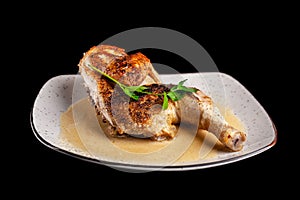 The concept of Georgian cuisine. Half a baked chicken in garlic sauce with crispy crust on a white plate, on black background