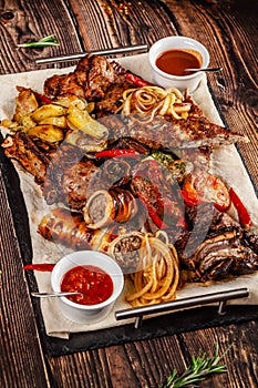 Concept of Georgian cuisine. Large meat board with shashlik, roasted meat, french fries, roast lamb and sauce. Serving dishes