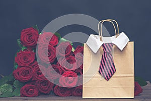 Concept of a gift for the day of lovers from a man.  large armful of red roses and a gift bag with a men`s tie