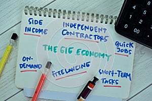 Concept of The Gig Economy write on book with keywords isolated on Wooden Table