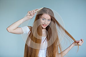 Concept of hair loss. Close up portrait of unhappy sad stressed young woman with long dry brown hair, isolated on grey