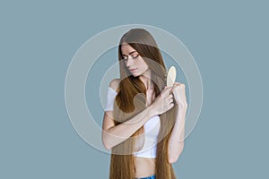 Concept of hair loss. Close up portrait of unhappy sad stressed young woman with long dry brown hair, isolated on grey