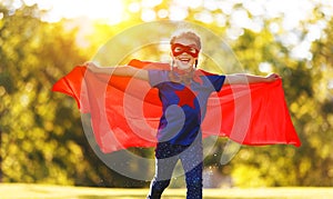 Concept happy child superhero hero in red cloak  in nature