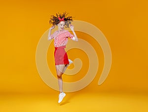 Concept happy emotional young woman in red  jumping   on yellow background