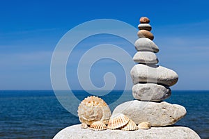 Concept of harmony and balance. Rock Zen of seashells on a background of summer sea.