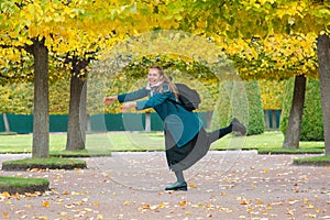 The concept of haste and tardiness. A woman is fooling around and having fun in the Park, against the background of yellow trees