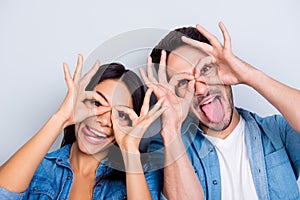 Concept of having funtime and grimacing, behaving like kids. Close up photo of two happy people making binoculars with their hand photo