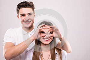 Concept of having funtime and grimacing, behaving like kids. Close up photo of two happy people making binoculars with their hands