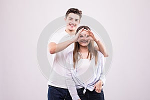 Concept of having funtime and grimacing, behaving like kids. Close up photo of two happy people making binoculars with their hands photo