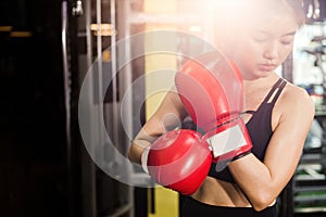 Concept of health-loving woman. Female boxer wearing red boxing gloves in fitness gym