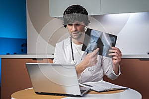 The concept of healthcare, medicine and people - a happy smiling male doctor with an X-ray scan of the spine conducts a