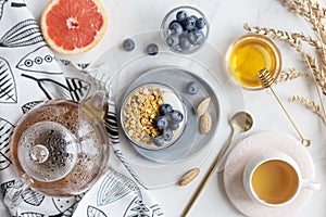 Concept of healthy breakfast. Oatmeal with nuts, berries and milk, honey, grapefruit and tea