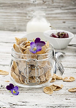 The concept of a healthy breakfast of whole wheat cereals, berries and edible flowers on a garden violet on a light