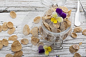 The concept of a healthy breakfast of whole wheat cereals, berries and edible flowers on a garden violet on a light