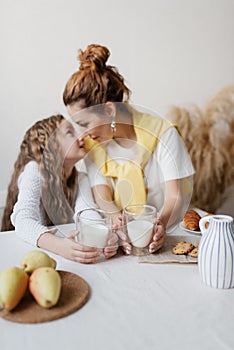 The concept of healthy eating. Mother and daughter have breakfast in the kitchen and drink milk