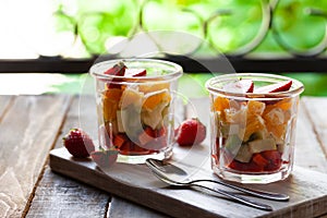 Concept of healthy food, clean eating. Low calories colorful sweet summer dessert. Homemade simple fruit salad in two glasses,