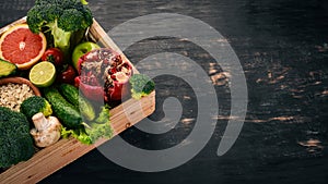 The concept of healthy food. Fresh vegetables, nuts and fruits in a wooden box. On a wooden background.