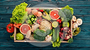 The concept of healthy food. Fresh vegetables, nuts and fruits in a wooden box. On a wooden background.