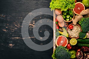 The concept of healthy food. Fresh vegetables, nuts and fruits in a wooden box. On a wooden background.