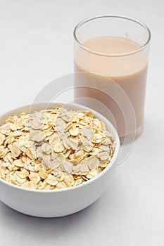 Concept of healthy food, Oat milk in glass and oat flakes in bowl over white background