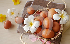 Concept healthy and happiness, Fresh brown chicken eggs in basket gift set decorated with white flowers on wooden table