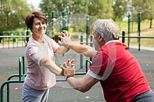 Concept of healthy lifestyle for elderly. Married couple raise each other and stretch each other hands