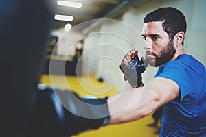 Concept of a healthy lifestyle.Hispanic muscular man fighter practicing kicks with punching black bag.Kick boxer boxing