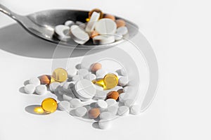 The concept of a healthy lifestyle, treatment of diseases and proper nutrition. Different pills in a spoon on a light background