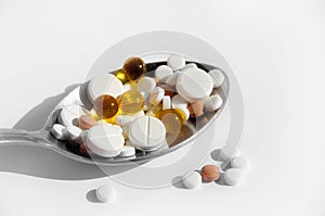 The concept of a healthy lifestyle, treatment of diseases and proper nutrition. Different pills in a spoon on a light background