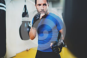 Concept of a healthy lifestyle.Young muscular man fighter practicing kicks with punching black bag.Kick boxer boxing as