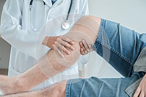 Concept healthy ,Male Patient in blue shirt visiting Doctor of Orthopedics examining injured leg and knee of male patient photo