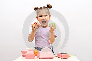 Concept of healthy and unhealthy food, little smiling blonde girl in purple T-shirt chooses between green apple and hamburger,