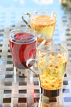 Concept of herbal tea. Variety of herbal teas in glass mugs. Healthy caffein-free drinks. Chamomile, hibiscus and linden teas