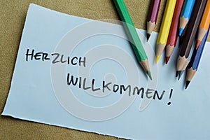 Concept of Herzlich Willkommen write on sticky notes isolated on Wooden Table