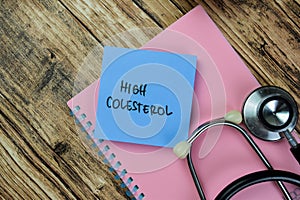 Concept of High Colesterol write on sticky notes with stethoscope isolated on Wooden Table photo