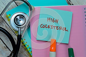 Concept of High Colesterol write on sticky notes with stethoscope isolated on Wooden Table photo