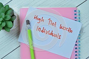 Concept of High Net Worth Individuals write on sticky notes isolated on Wooden Table