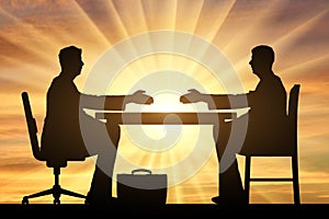 Concept hiring process. Silhouette of two men sitting at a table and stretching out their hands for a handshake