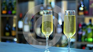 Concept of holiday, date. two glasses with champagne on the background of a rack with bottles