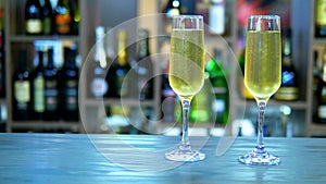 Concept of holiday, date. two glasses with champagne on the background of a rack with bottles