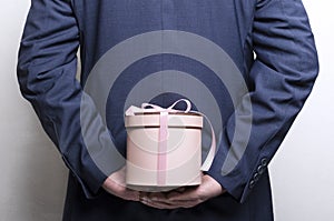 Concept of holiday gift.Man wearing blue jacket and prepared romantic gift in the pink box