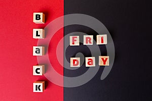 Concept of holidays sales. On a red and black background are wooden cubes with the inscription black Friday. Flat lay. Copy space